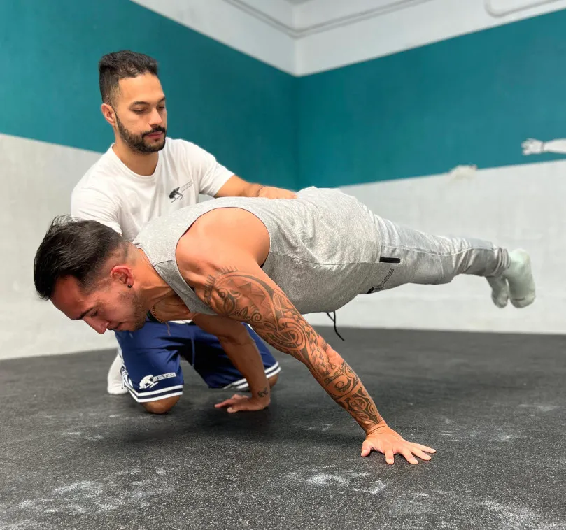 Jhonnatan supervisando a un alumno practicando planche en JAP Calisthenics